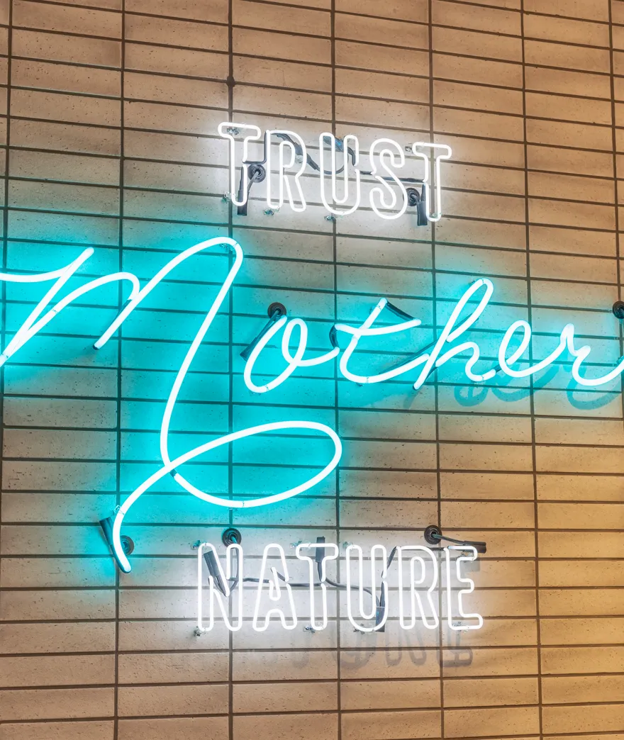 Trust Mother Nature neon sign on the brick wall at Coastal Green