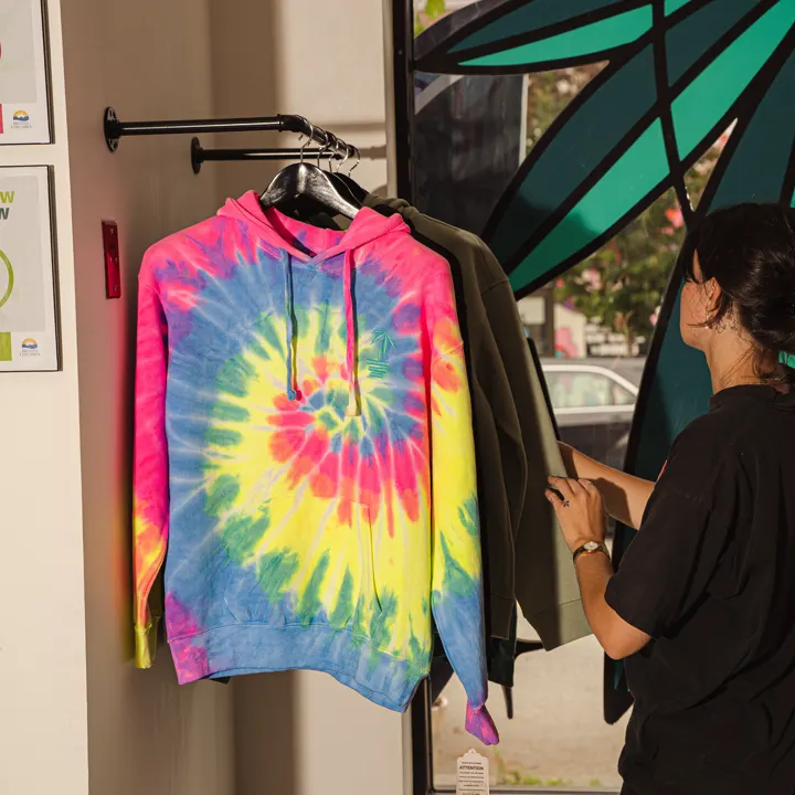 Tie-dye hoodie on the Coastal Green merch rack